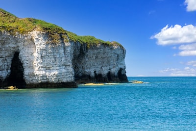 During the day under the blue sky blue sea, on the edge of brown and green mountains
